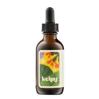 A glass bottle with a dropper containing plant food, labeled 'kelpy', with a colorful floral label on the front.