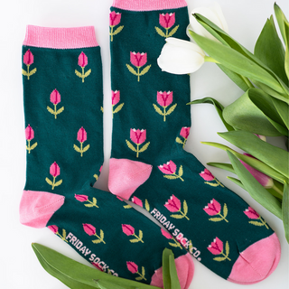 A pair of green mismatched socks with a floral pattern