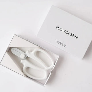 A pair of white gardening shears with a Teflon-coated blade, displayed in an open box