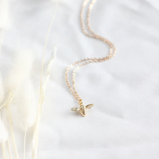 A delicate honeybee necklace with a gold chain and a small bee pendant
